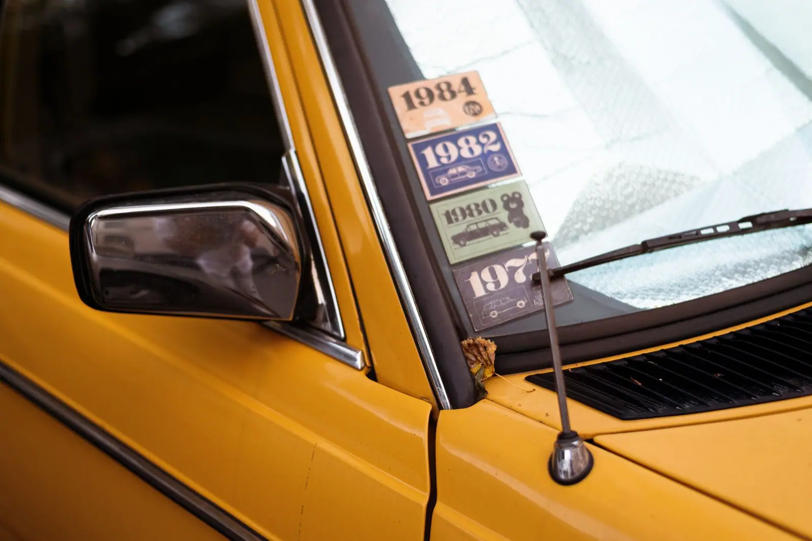 Paper stickers displayed in the corner of a yellow car windscreen