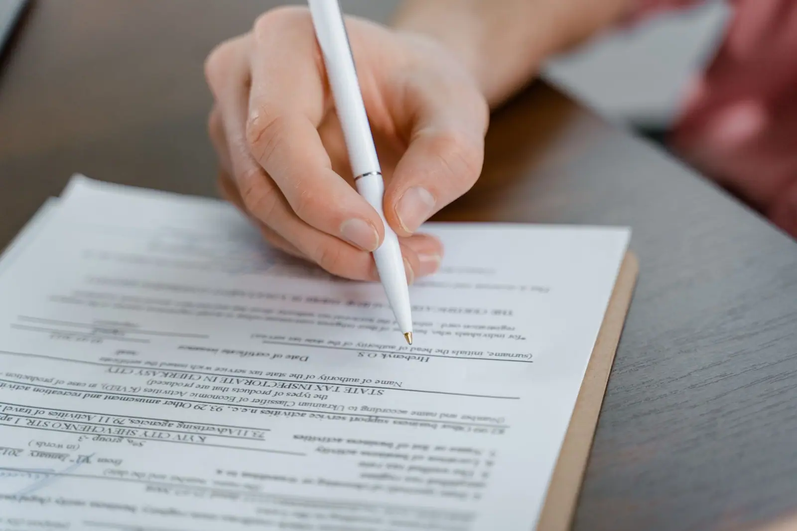 A hand holding a pen above a printed form on a table