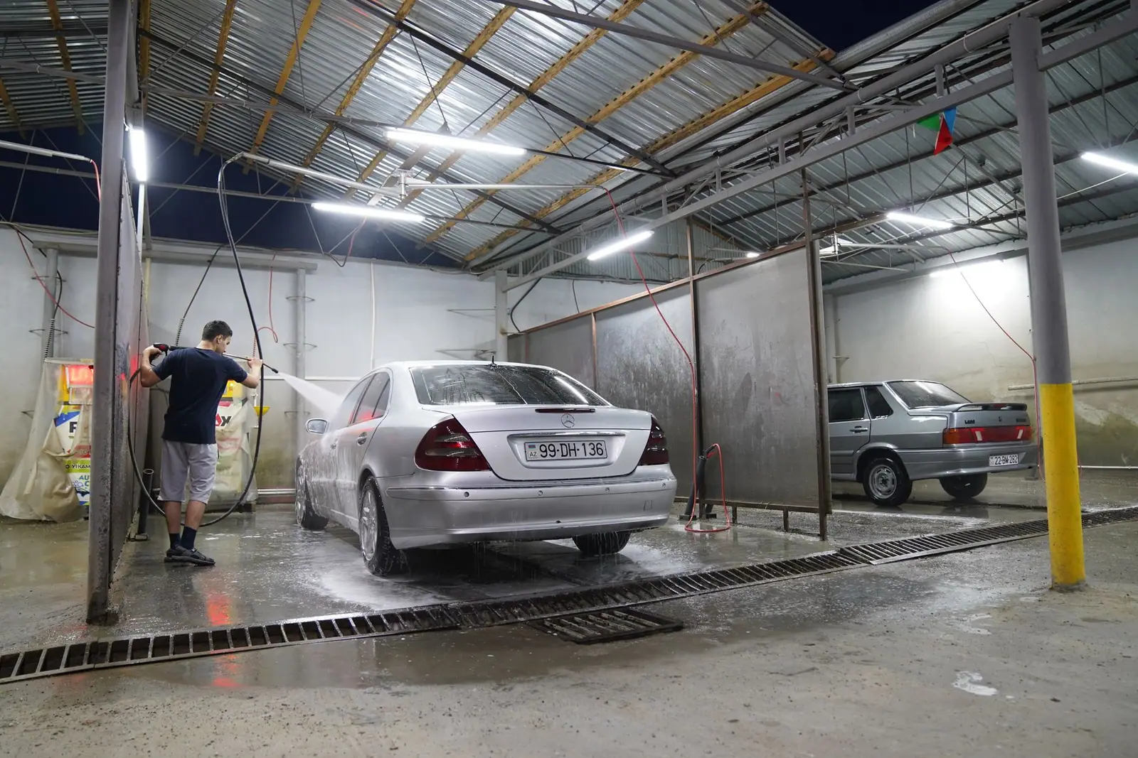 A person washing a vehicle inside a car wash bay
