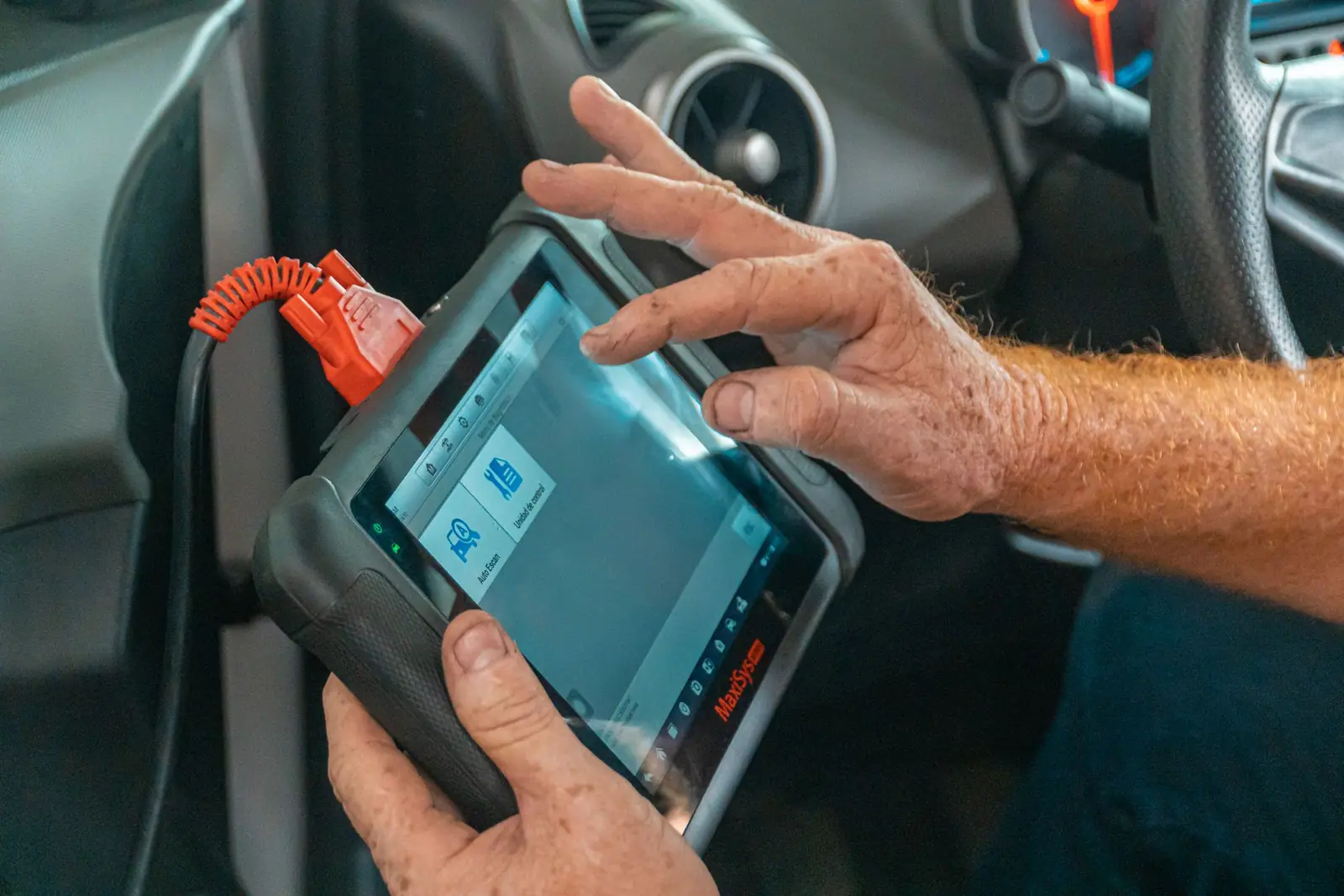 A person holding a connected diagnostic tablet inside a car