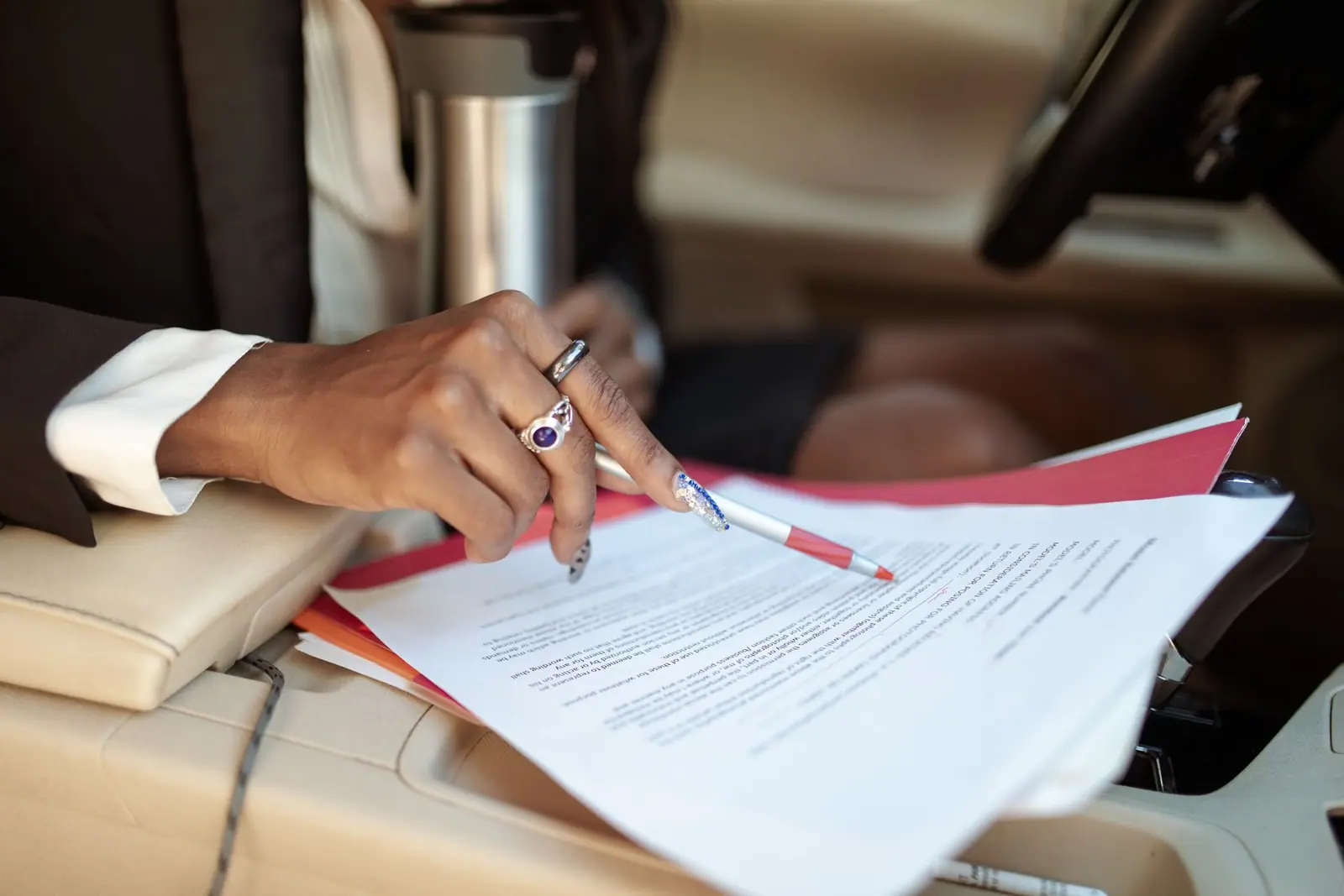 A person marking a paper with a pink pen beside other documents