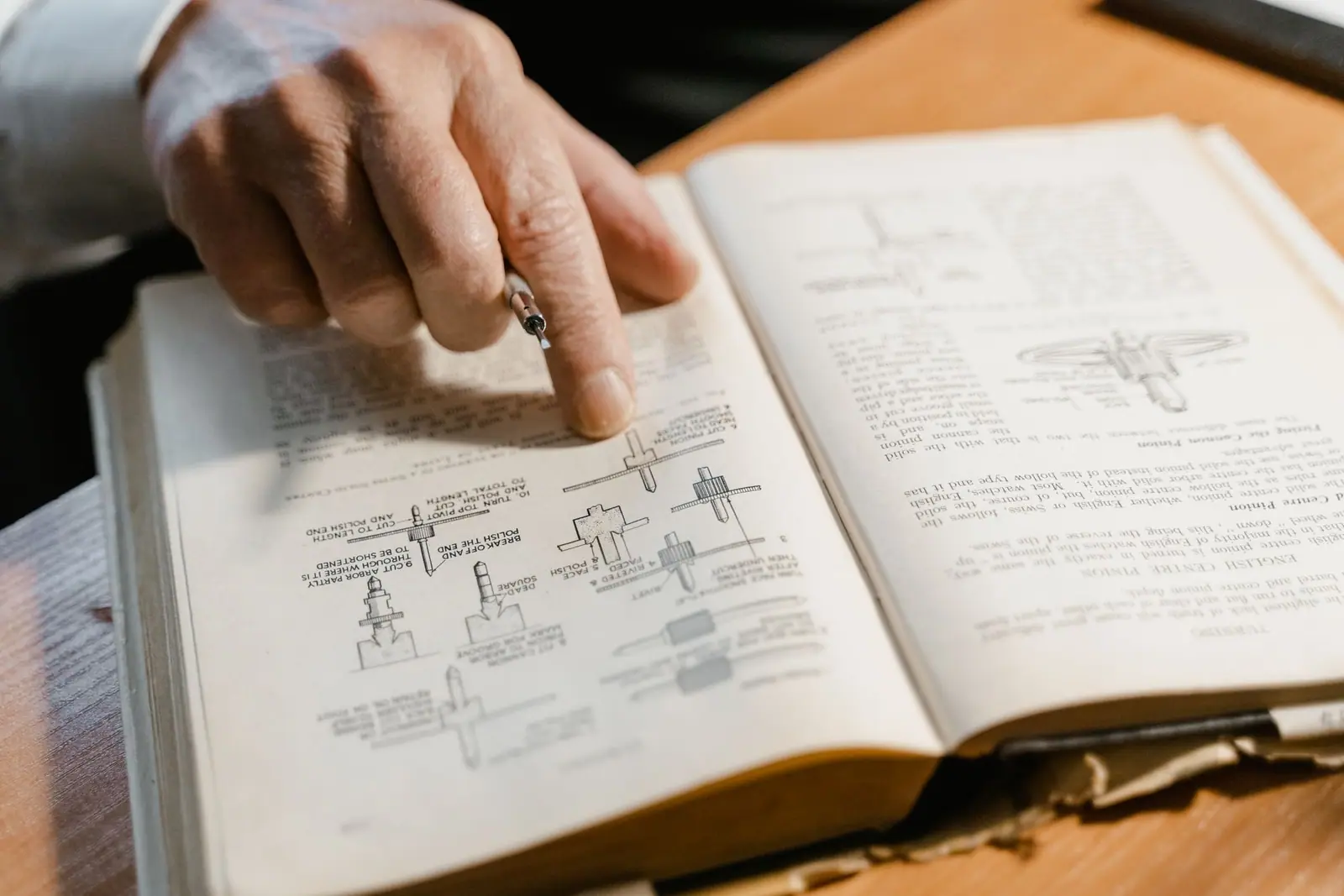 A finger pointing at a page in an open printed manual